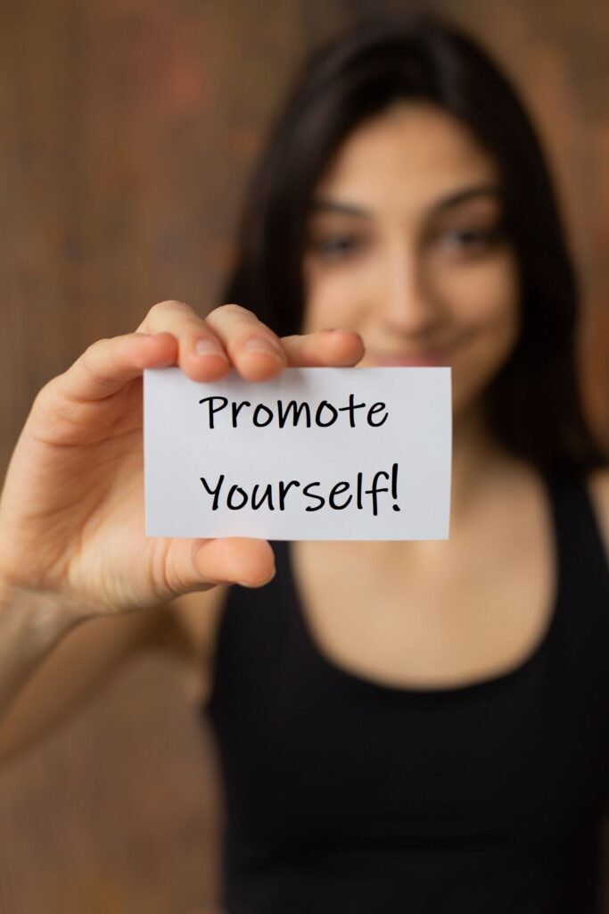 Woman holding card that says Promote Yourself!