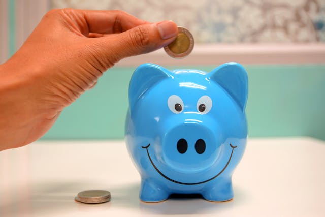 dropping a coin into a smiling piggy bank